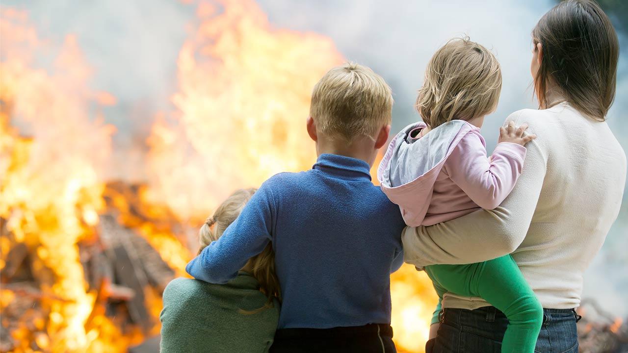 Brandschutz - Frau mit Kindern vor brennenden Haus