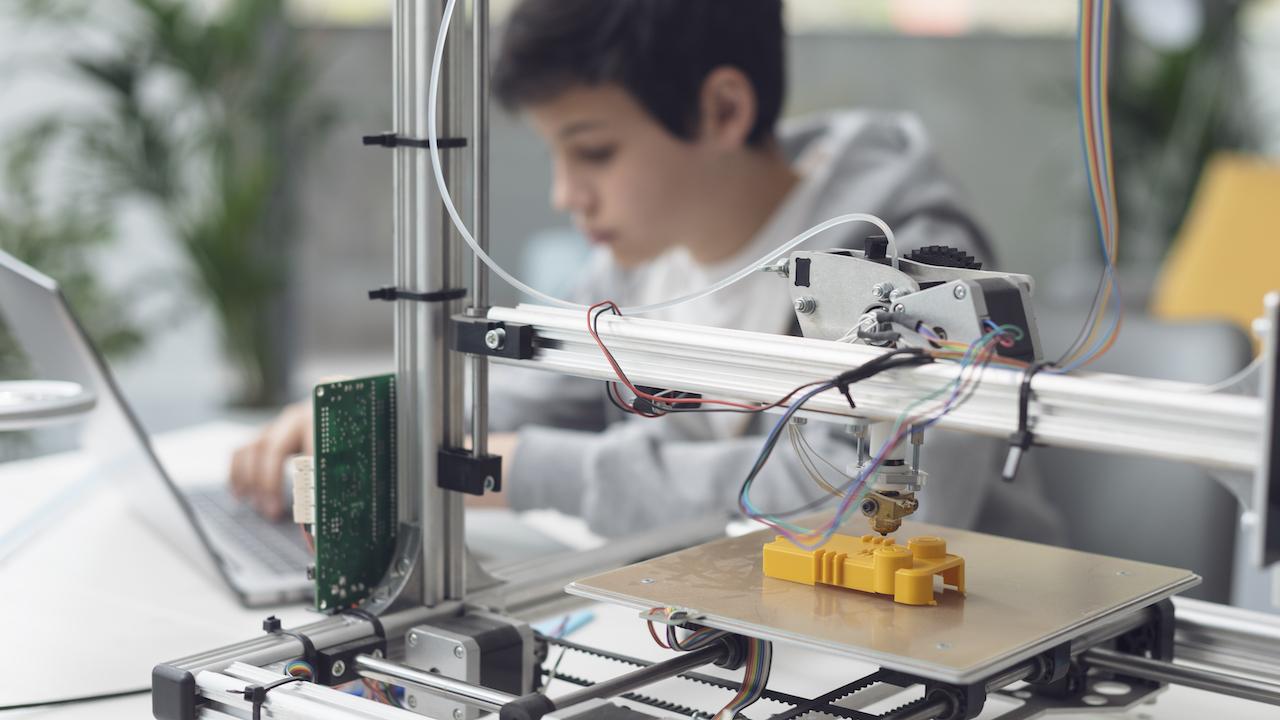 3D-Drucker - Junge am Laptop erstellt mit Drucker ein gelbes Spielzeug