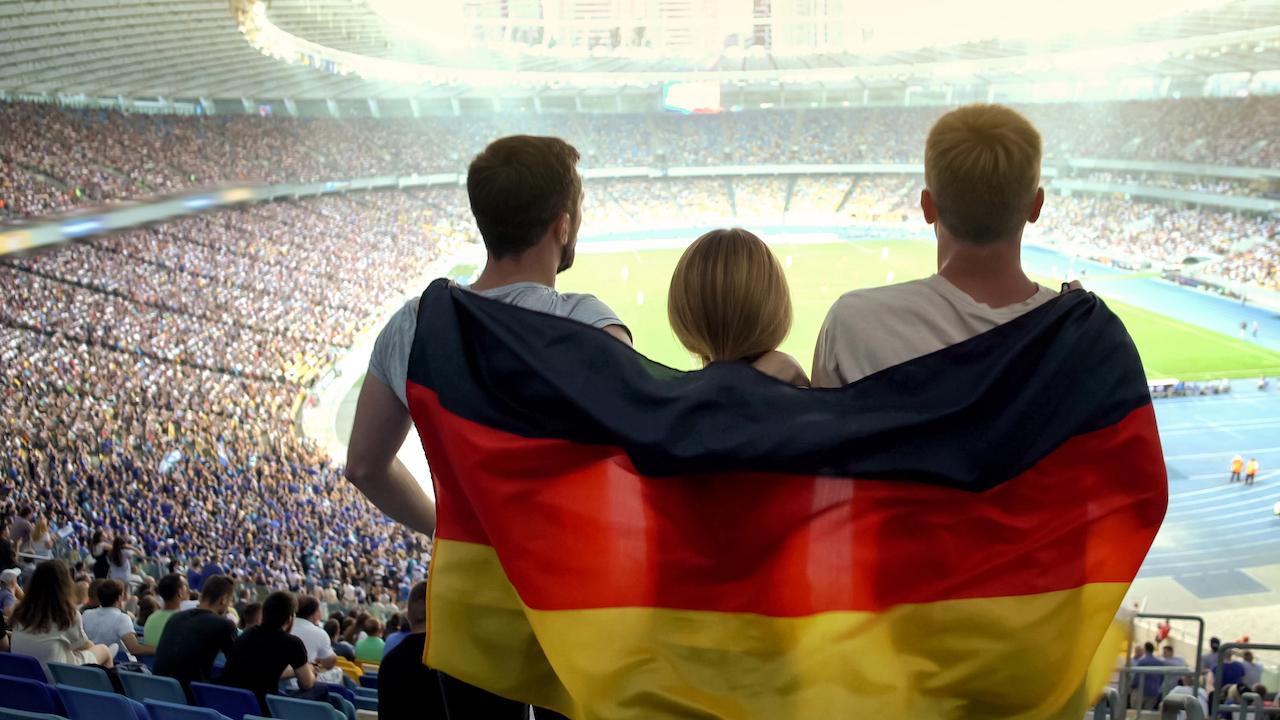 Fußball-Europameisterschaft 2024 - Menschen mit Deutschland-Flagge stehen im Fußballstadion