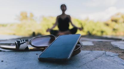 Digitales Detox - Frau im Hintergrund meditiert und Handy ist ausgeschaltet