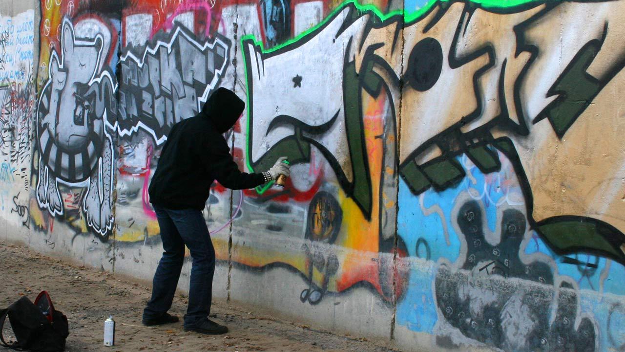 Graffiti - Einstieg in die Hobby-Malerei / ein Mann sprüht Graffiti 
