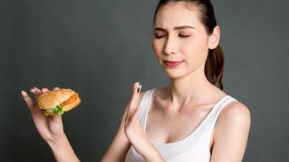 So bereiten Sie sich perfekt aufs Fasten vor - Frau hält einen Burger in der Hand